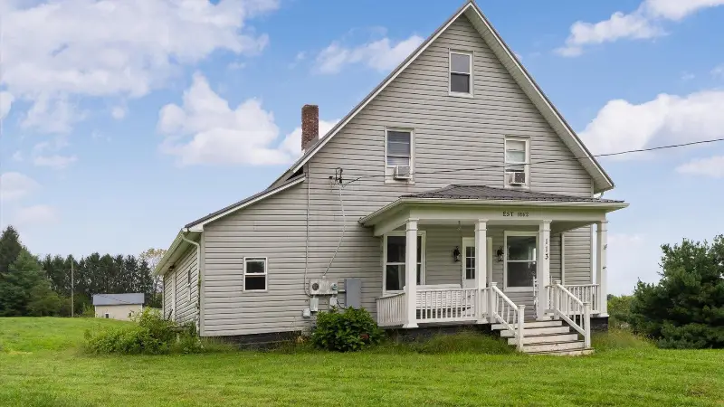 Gray two-story farmhouse with a white front porch marked Est 1862 at 113 Mill Street, Glenford, Ohio